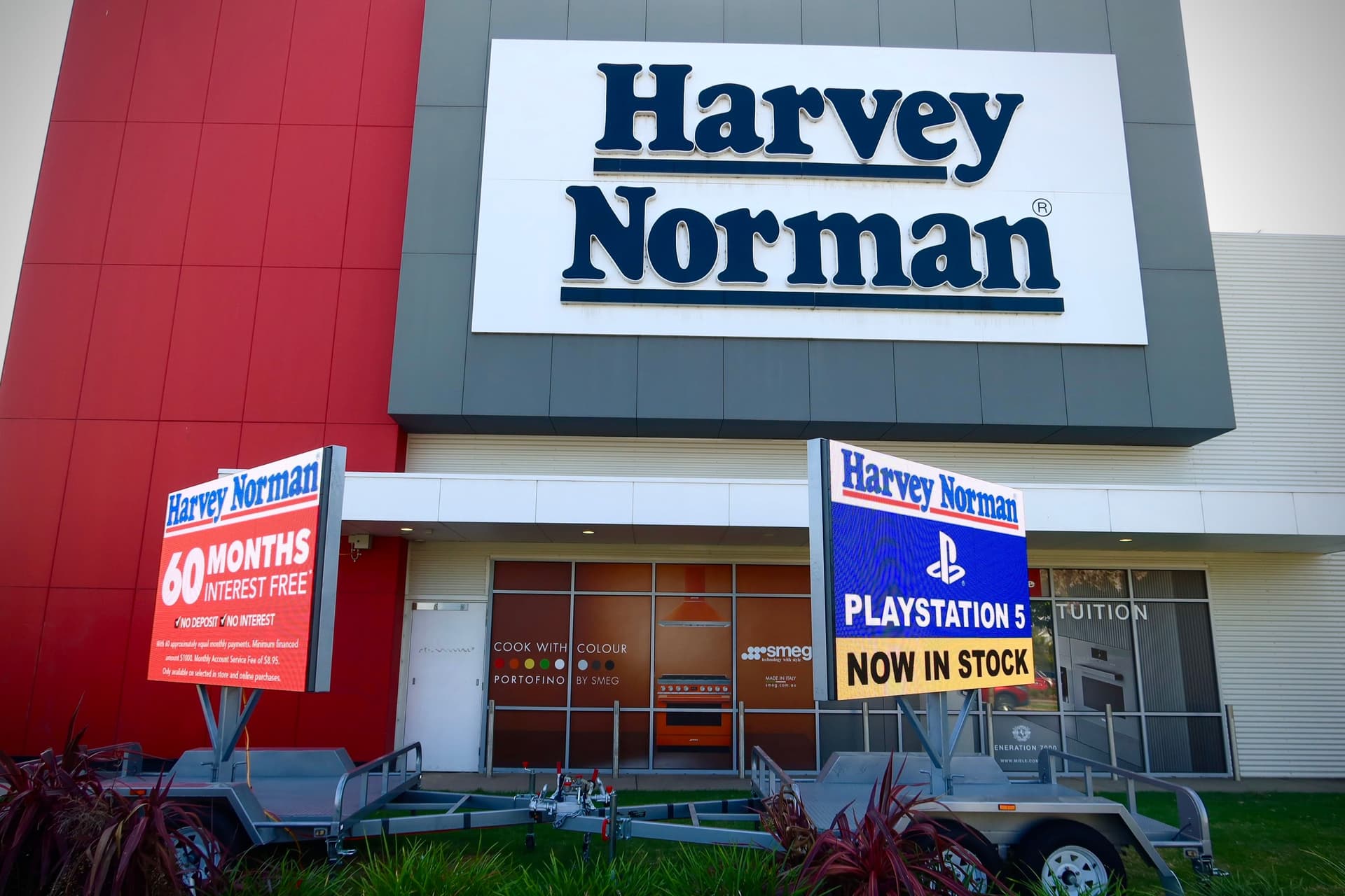 Two LED trailer screens parked in front of a Harvey Norman store, showing store promotions.