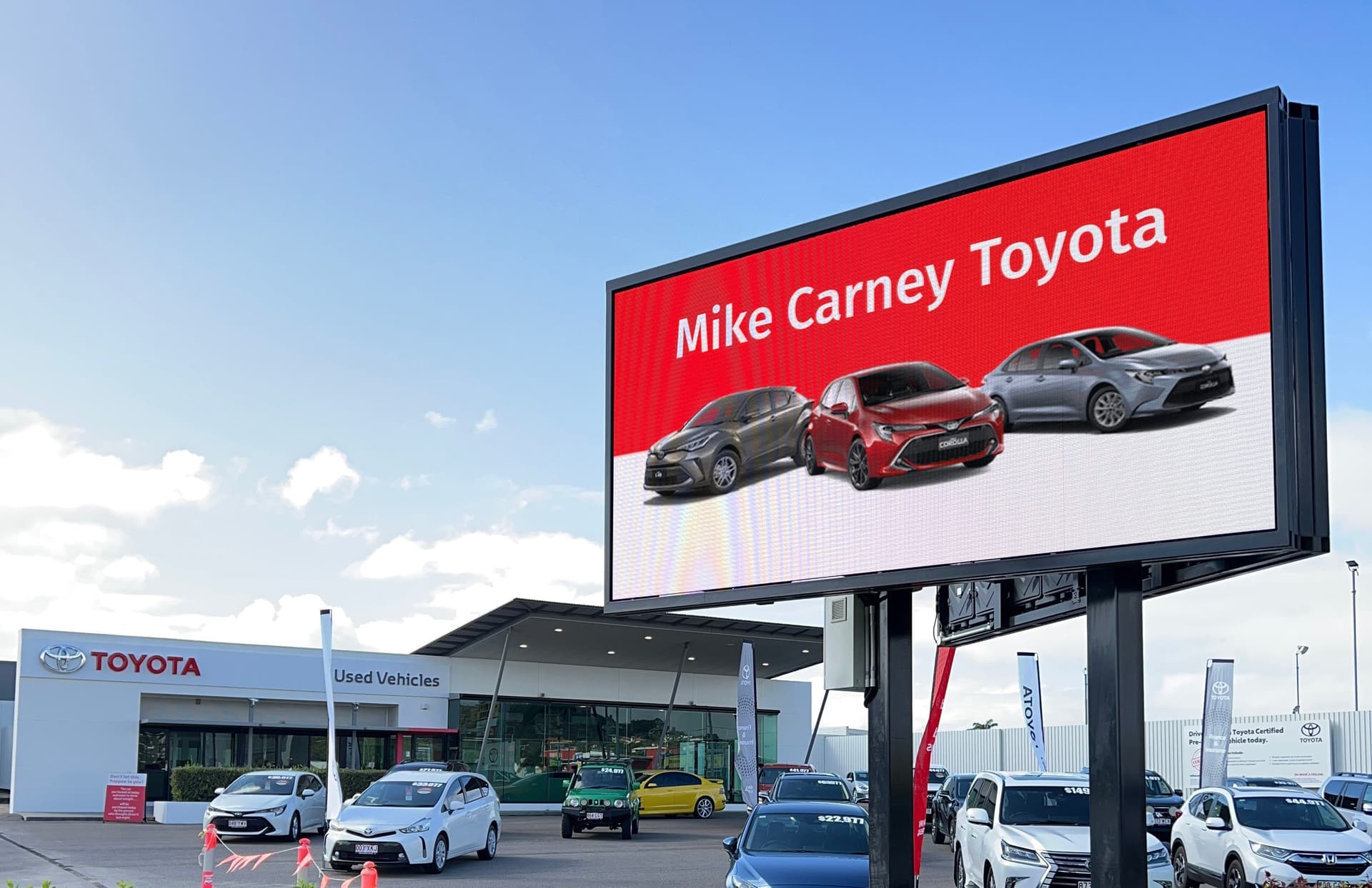 Large LED billboard on posts at the Mike Carney Toyota car yard, showing a Toyota ad.
