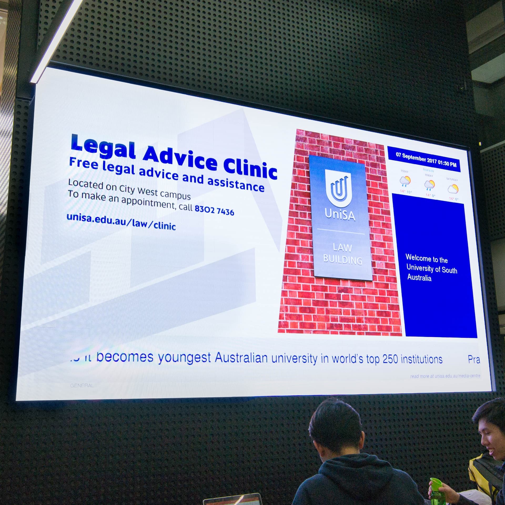 Large indoor LED screen on a wall, showing a legal advice clinic ad.