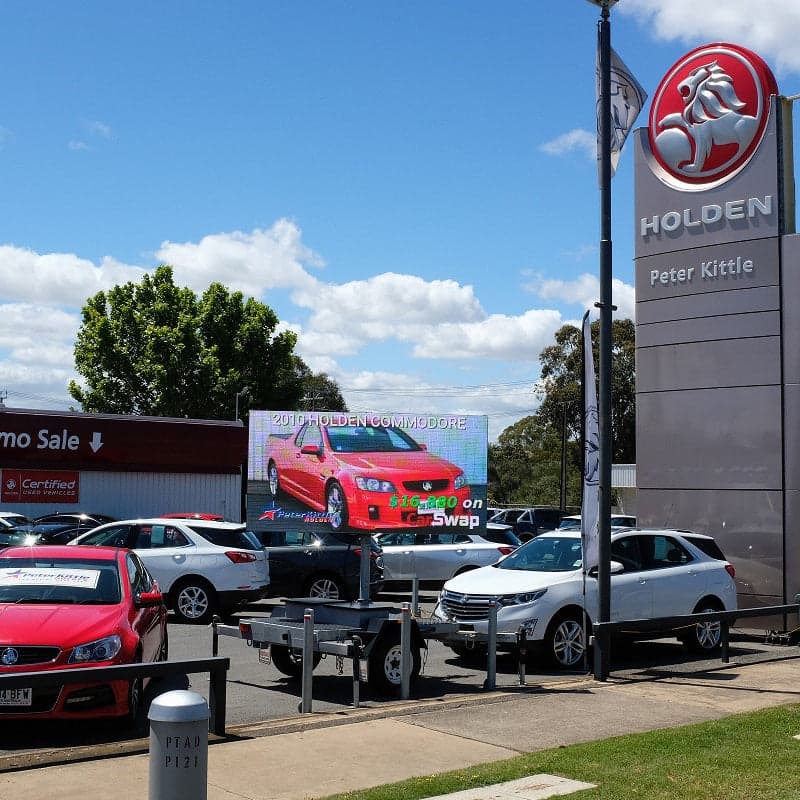 LED trailer screen parked at a car yard, showing a used car ad.