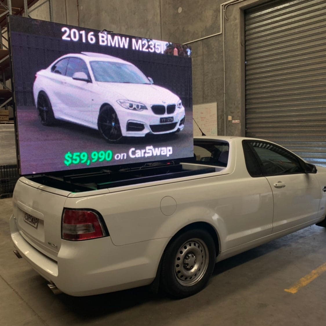 LED screen on the tray of a ute, showing a BMW for sale.