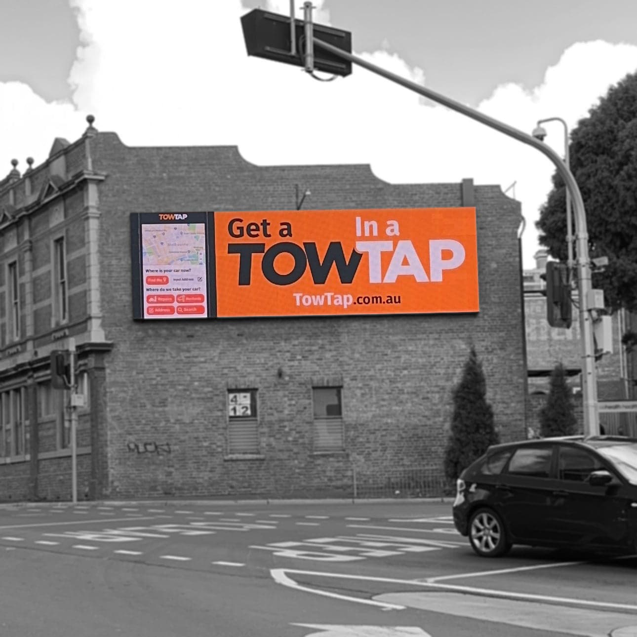 Wall-mounted LED sign on a brick building at a street corner, showing an app ad.