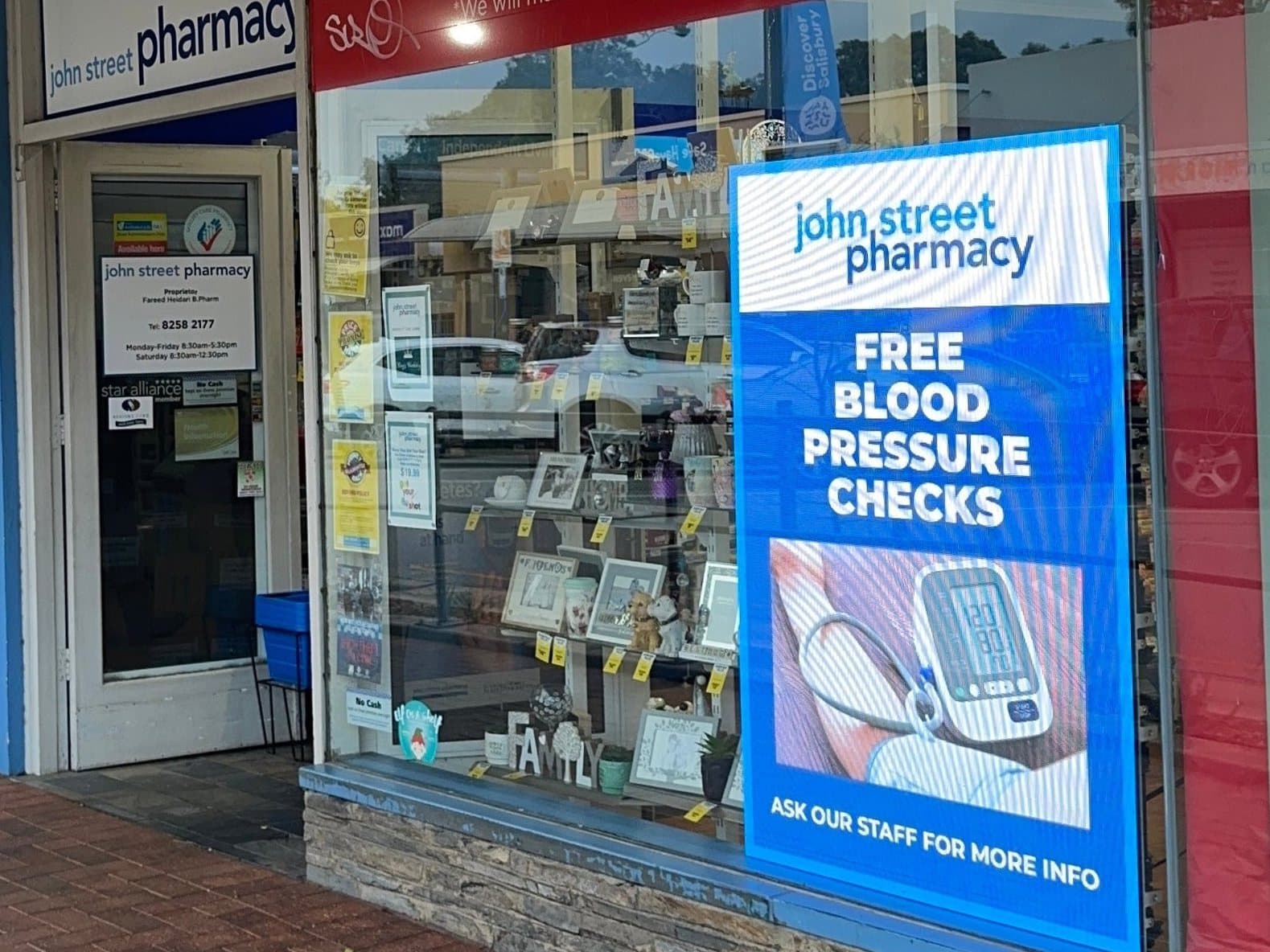 Portrait LED sign in a pharmacy window, promoting free blood pressure checks.